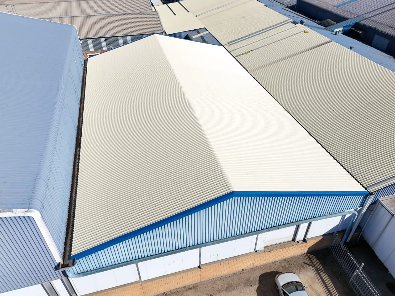 Aerial view of a completed commercial warehouse roof replacement with light-coloured corrugated panels