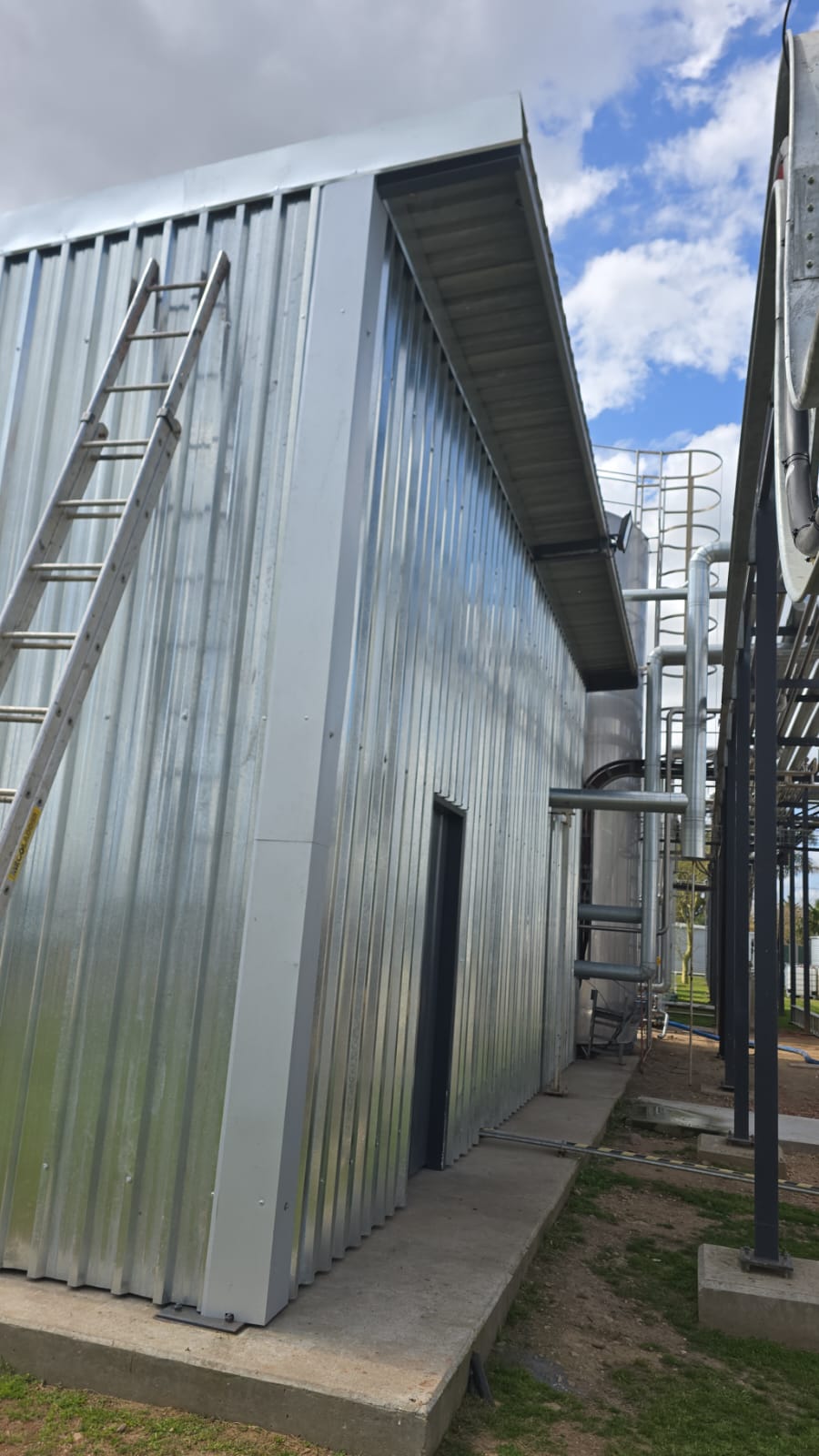 Industrial steel-clad shed exterior with corrugated siding and adjacent piping infrastructure