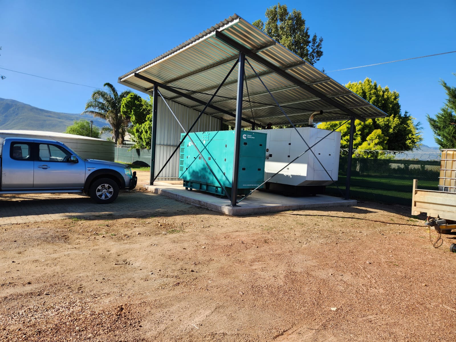 Commercial backup generators installed on a concrete plinth under a steel canopy structure