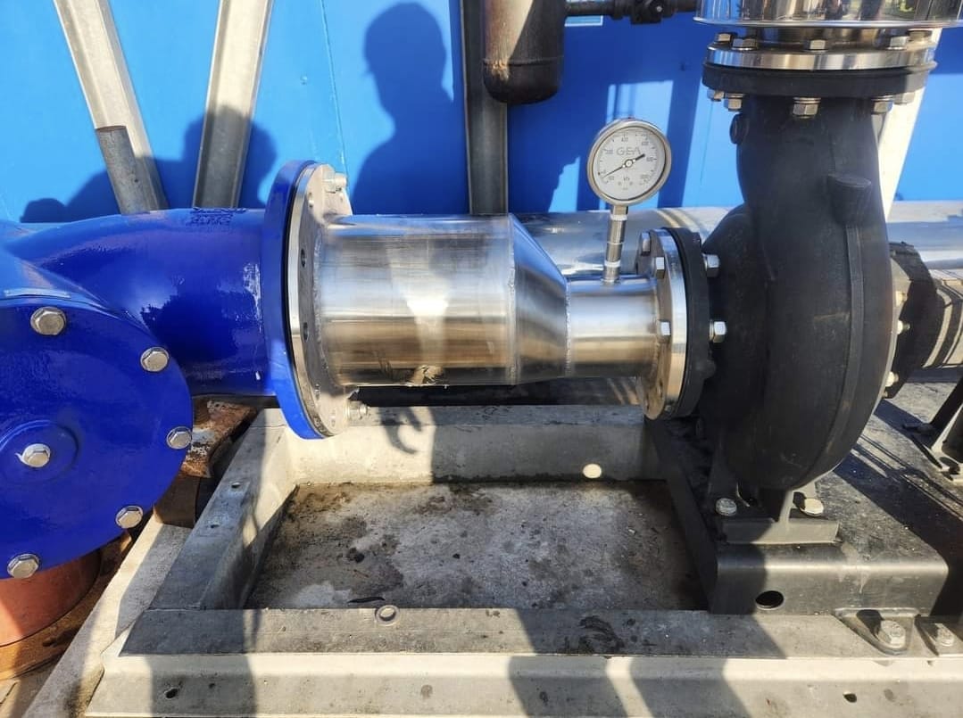 Industrial pump and piping installation with stainless steel fittings and pressure gauge